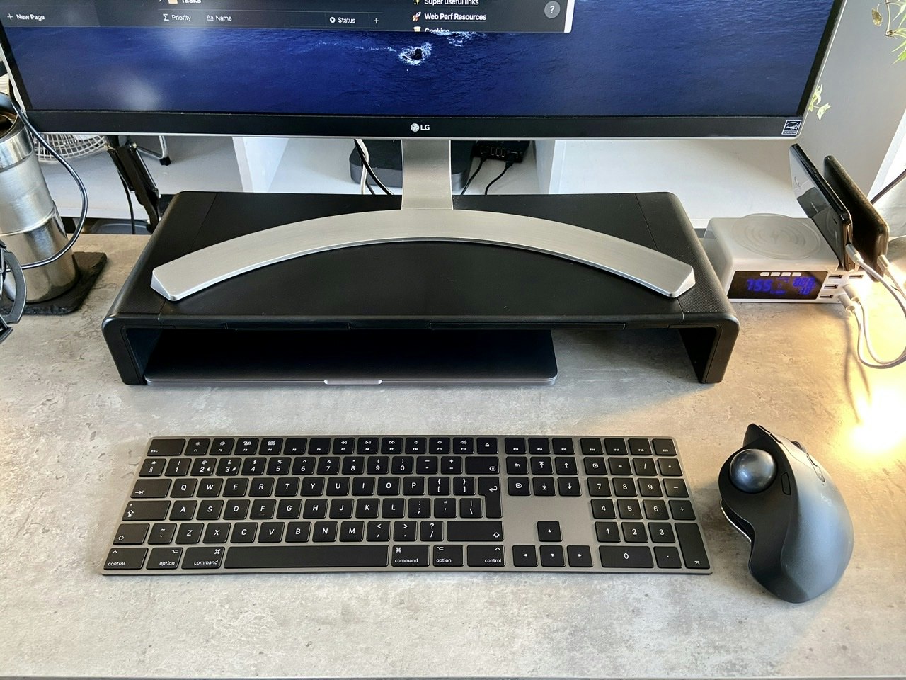 A dark magic keyboard on my desk, next to a track ball